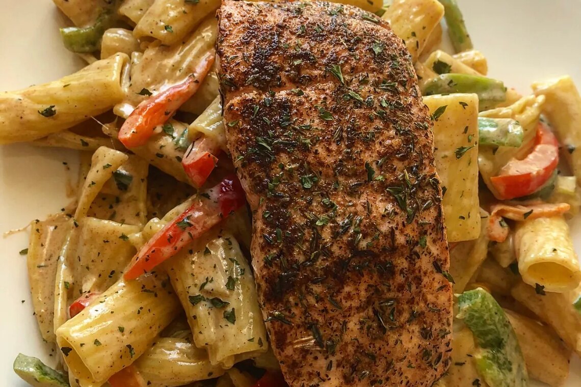 Blackened salmon fillet over rigatoni rasta pasta with peppers