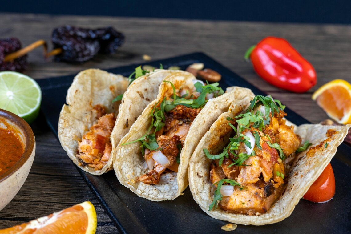 Three shrimp tacos plated with lime